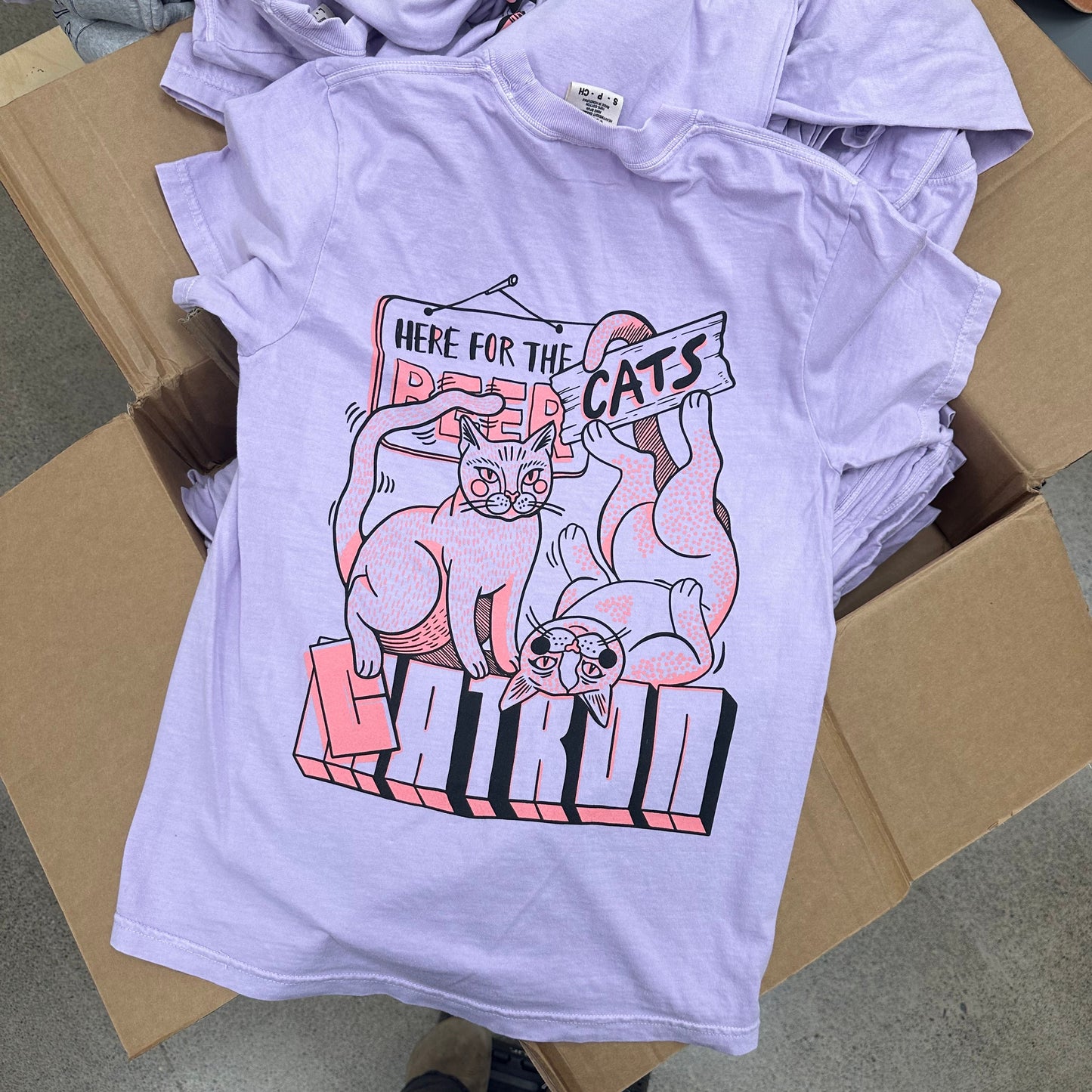 Stack of t-shirts with a graphic design on a cardboard box featuring Ricky bobby and Maurice